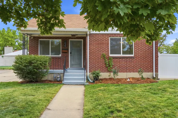 Brick exterior with white trim, gray entry door, and a manicured lawn