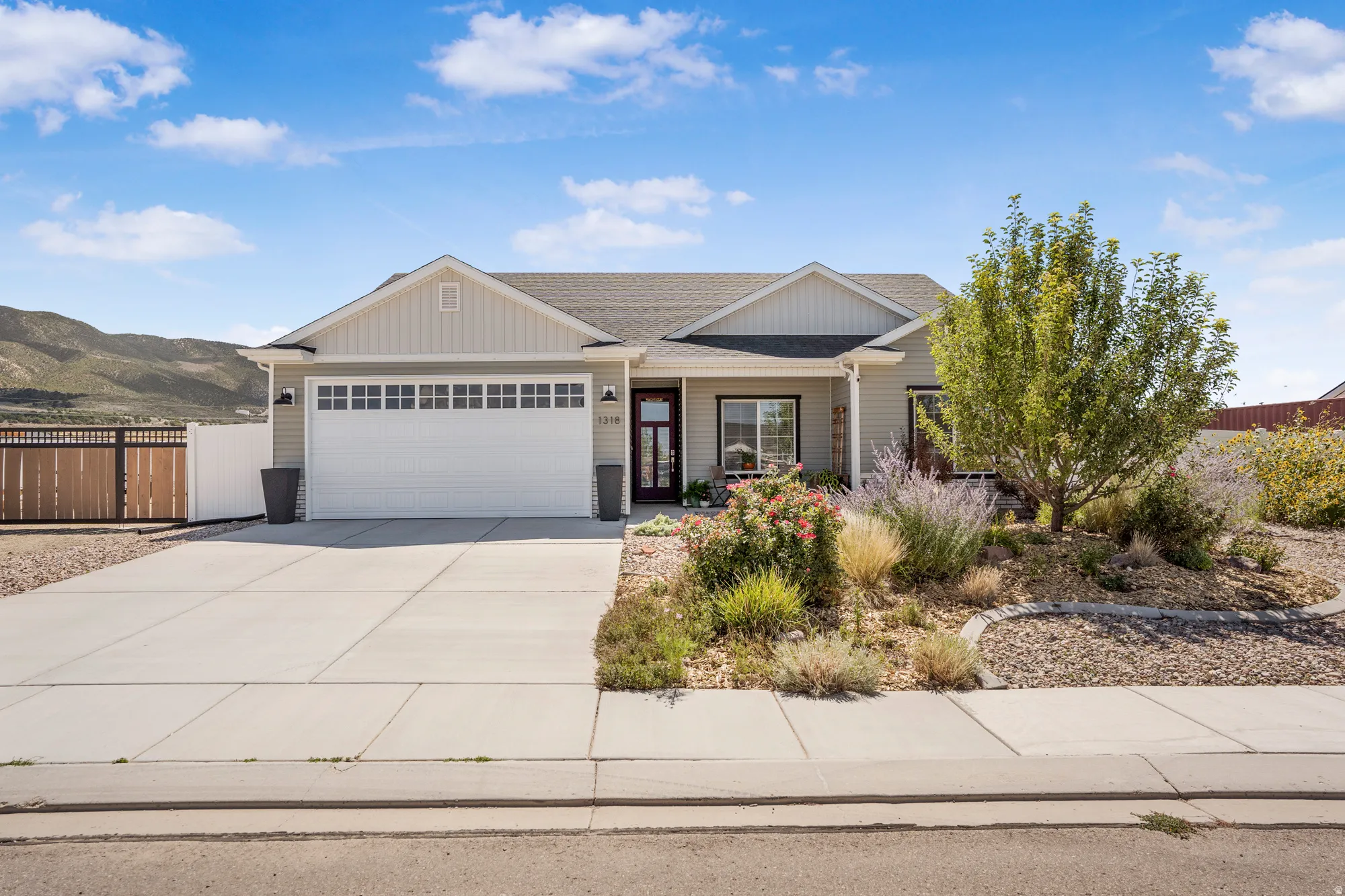 Single-story residence featuring light-toned siding, a two-car garage with transom windows, and a concrete driveway
