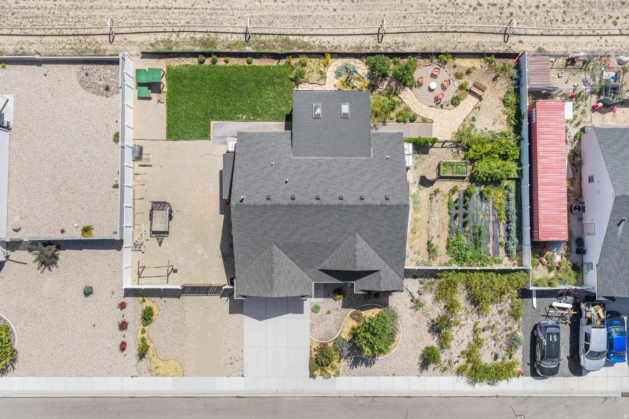 Expansive backyard featuring a manicured lawn, paved patio area, and raised garden beds
