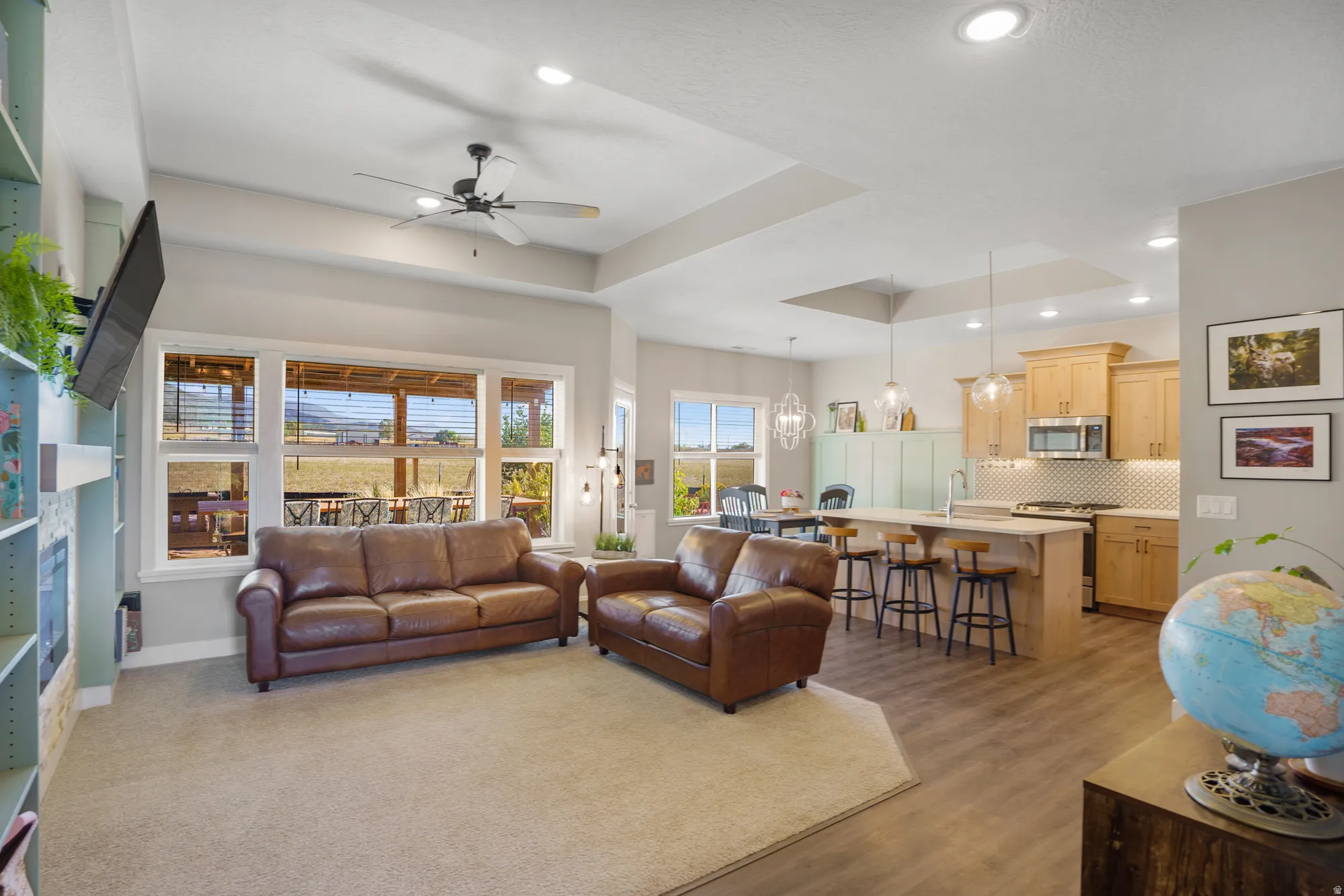 Expansive living area with recessed lighting, tray ceiling, and a ceiling fan