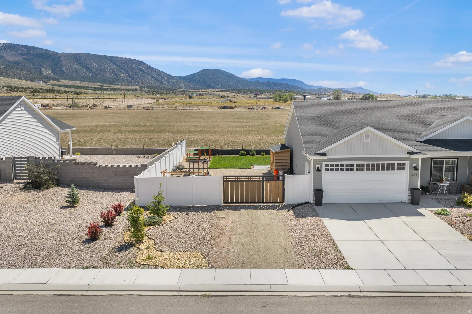 Landscaped front yard with gravel, concrete driveway, and mountain backdrop