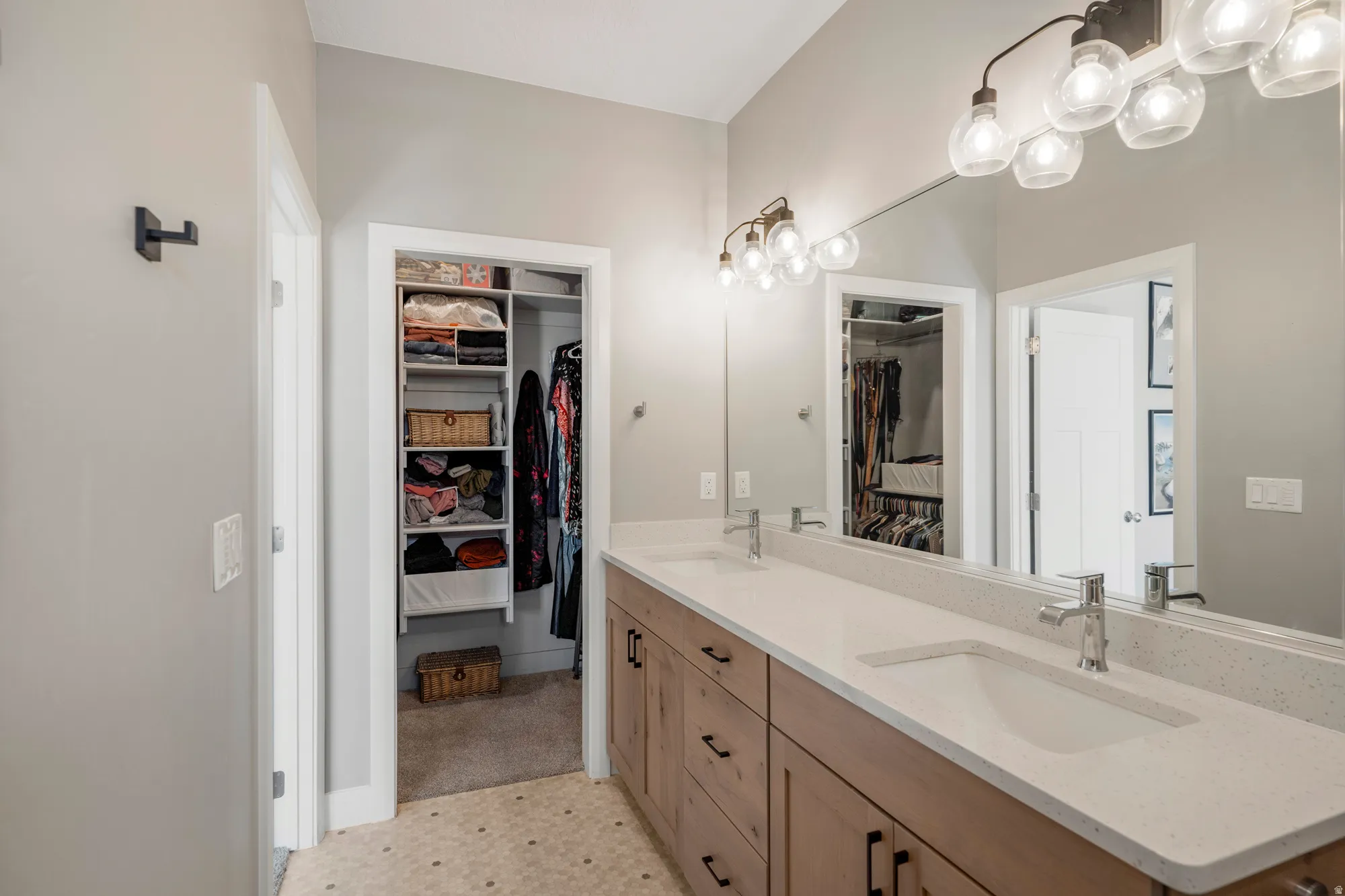 Dual vanity with undermount sinks, light wood-finish cabinetry, and a full-width mirror
