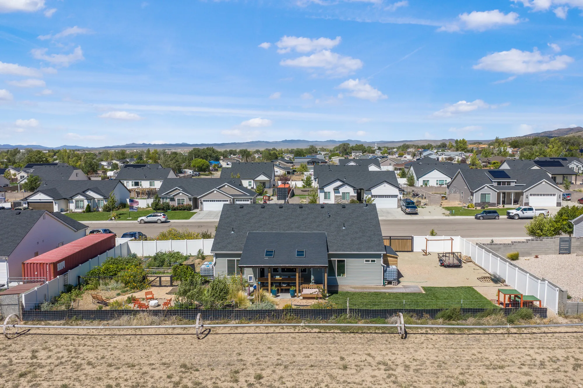 Expansive backyard featuring a covered patio, a manicured lawn area, and a fenced perimeter