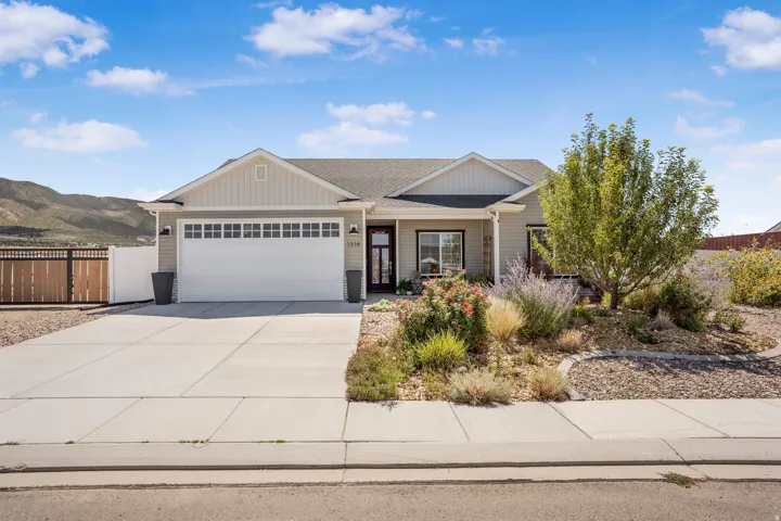 Single-story residence featuring light-toned siding, a two-car garage with transom windows, and a concrete driveway