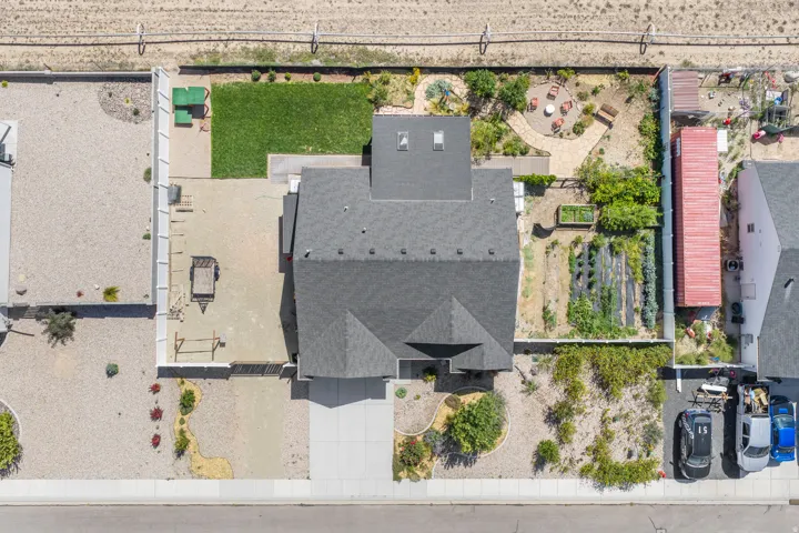Expansive backyard featuring a manicured lawn, paved patio area, and raised garden beds