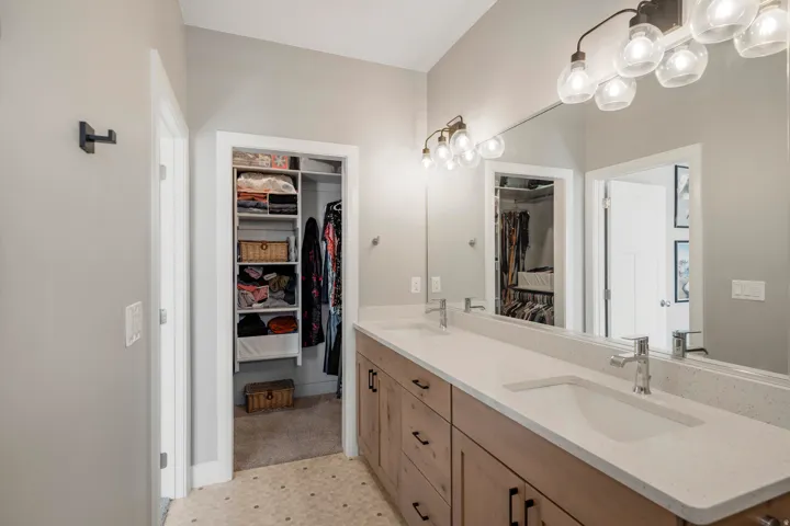 Dual vanity with undermount sinks, light wood-finish cabinetry, and a full-width mirror