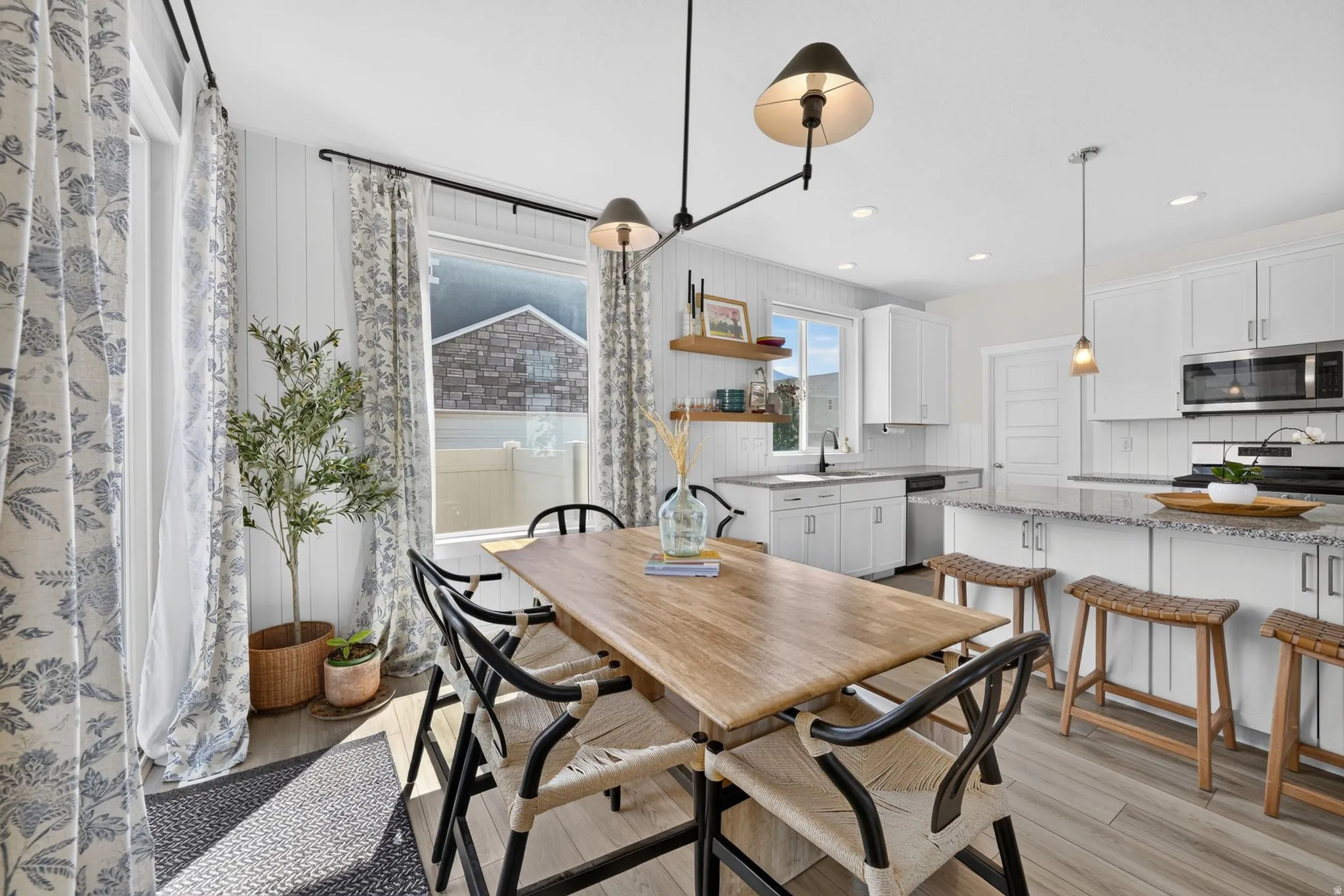Open-concept kitchen and dining area featuring light wood-finish flooring, white cabinetry, and a granite-style island