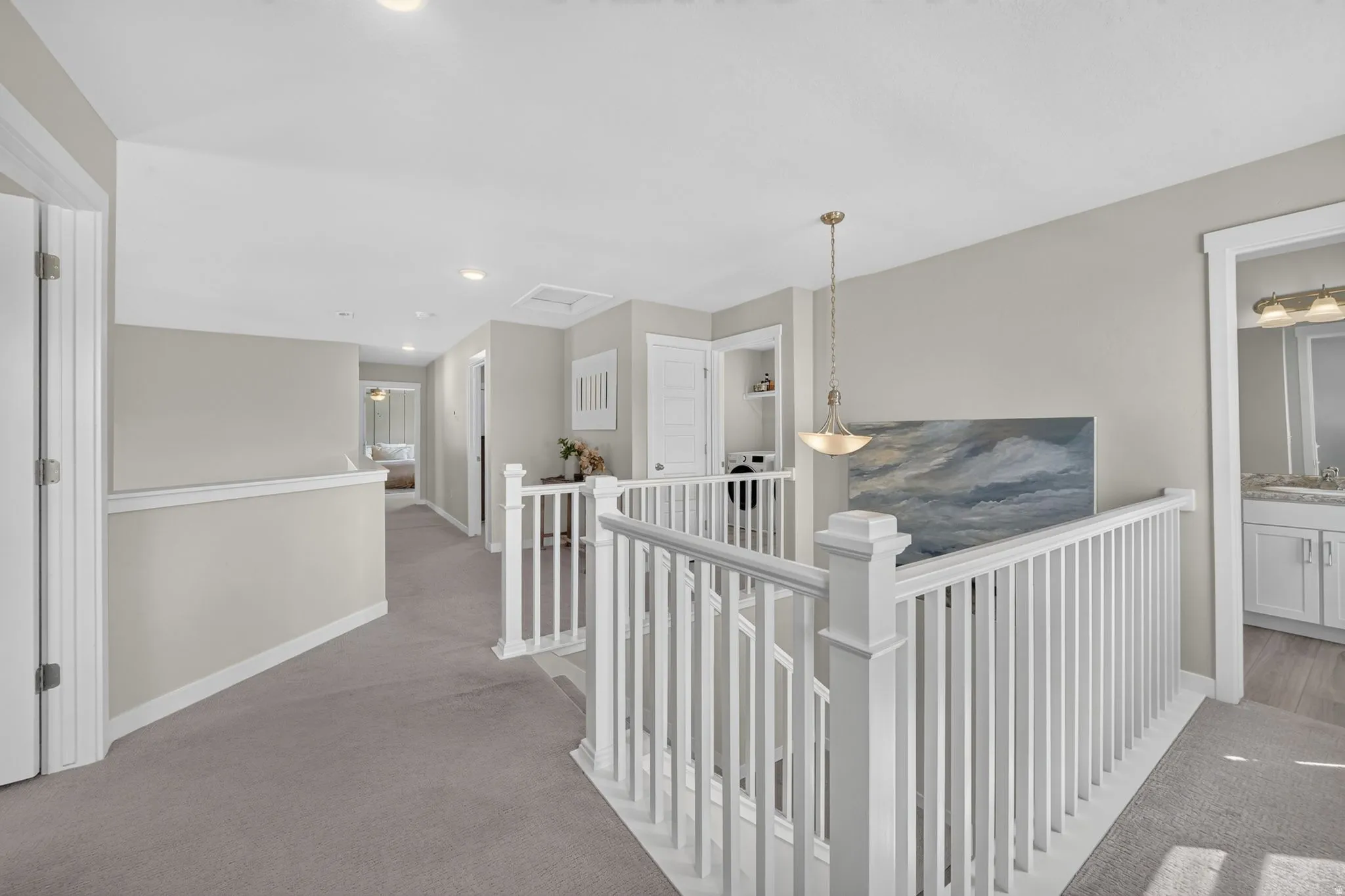 Upper-level hallway featuring a white balustrade, recessed lighting, and carpet flooring