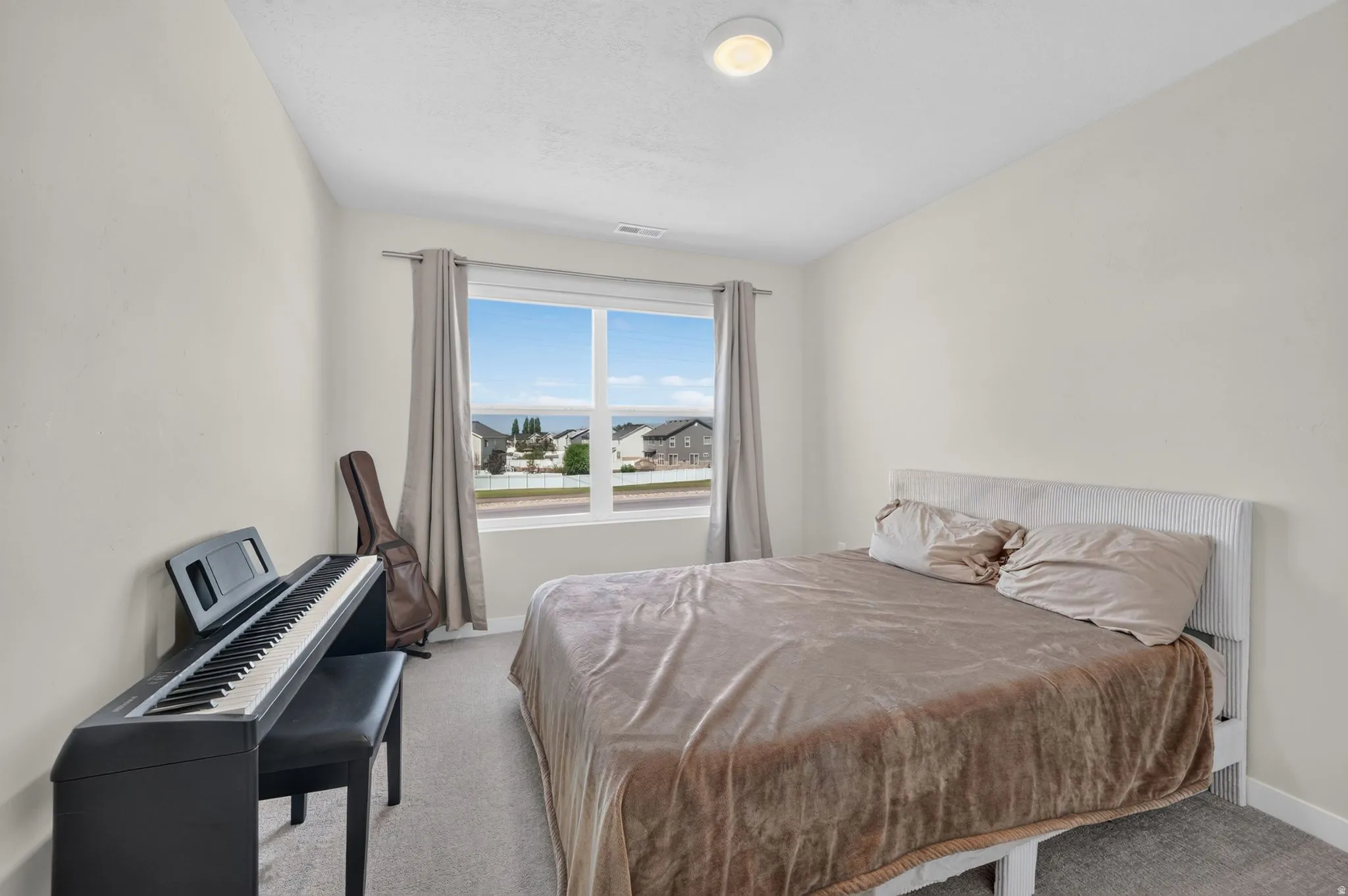 Carpeted flooring, vaulted ceiling, and a large window with neutral drapery