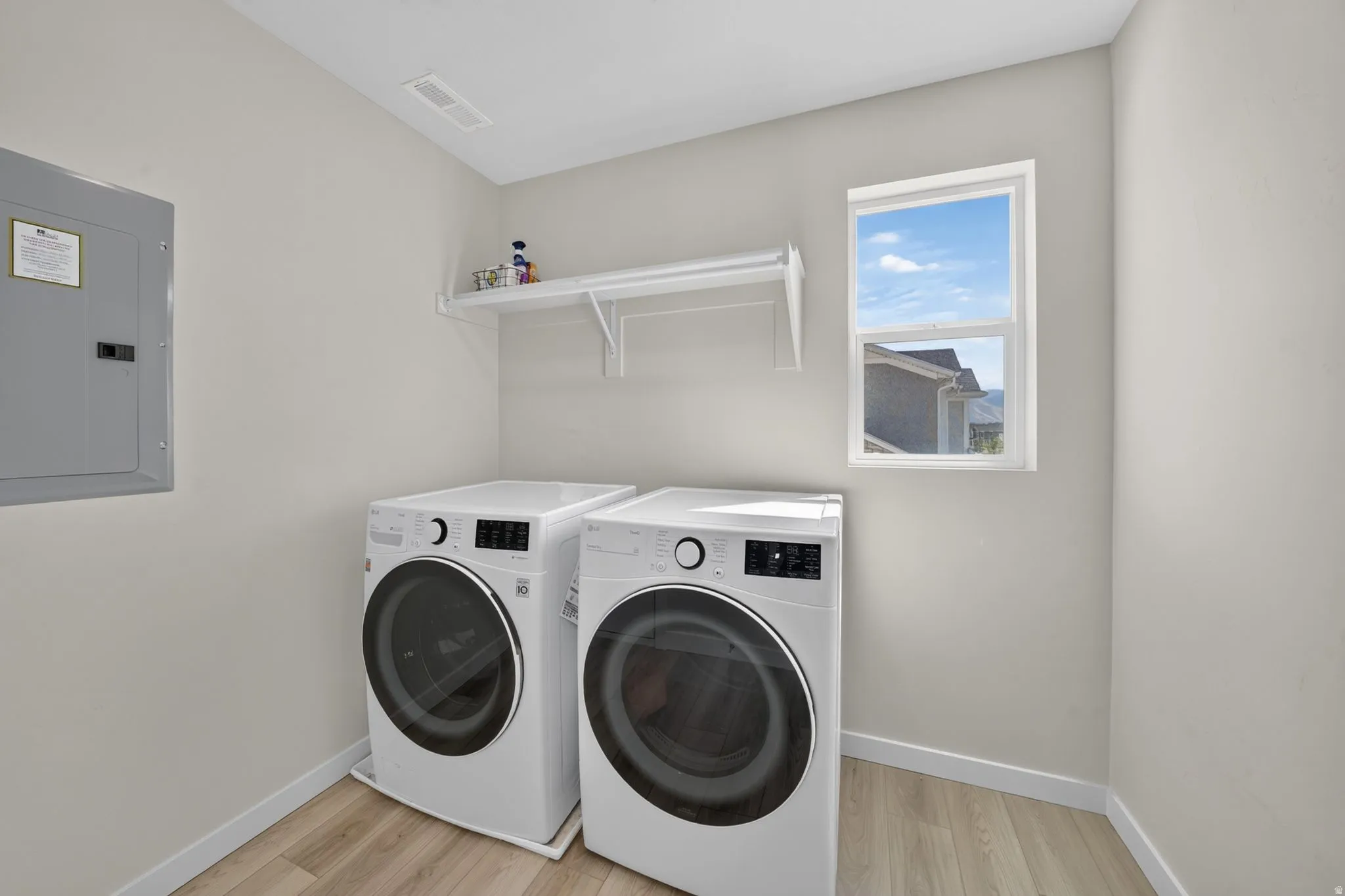 Laundry area featuring light wood-finish flooring, a white window, and a built-in white shelf