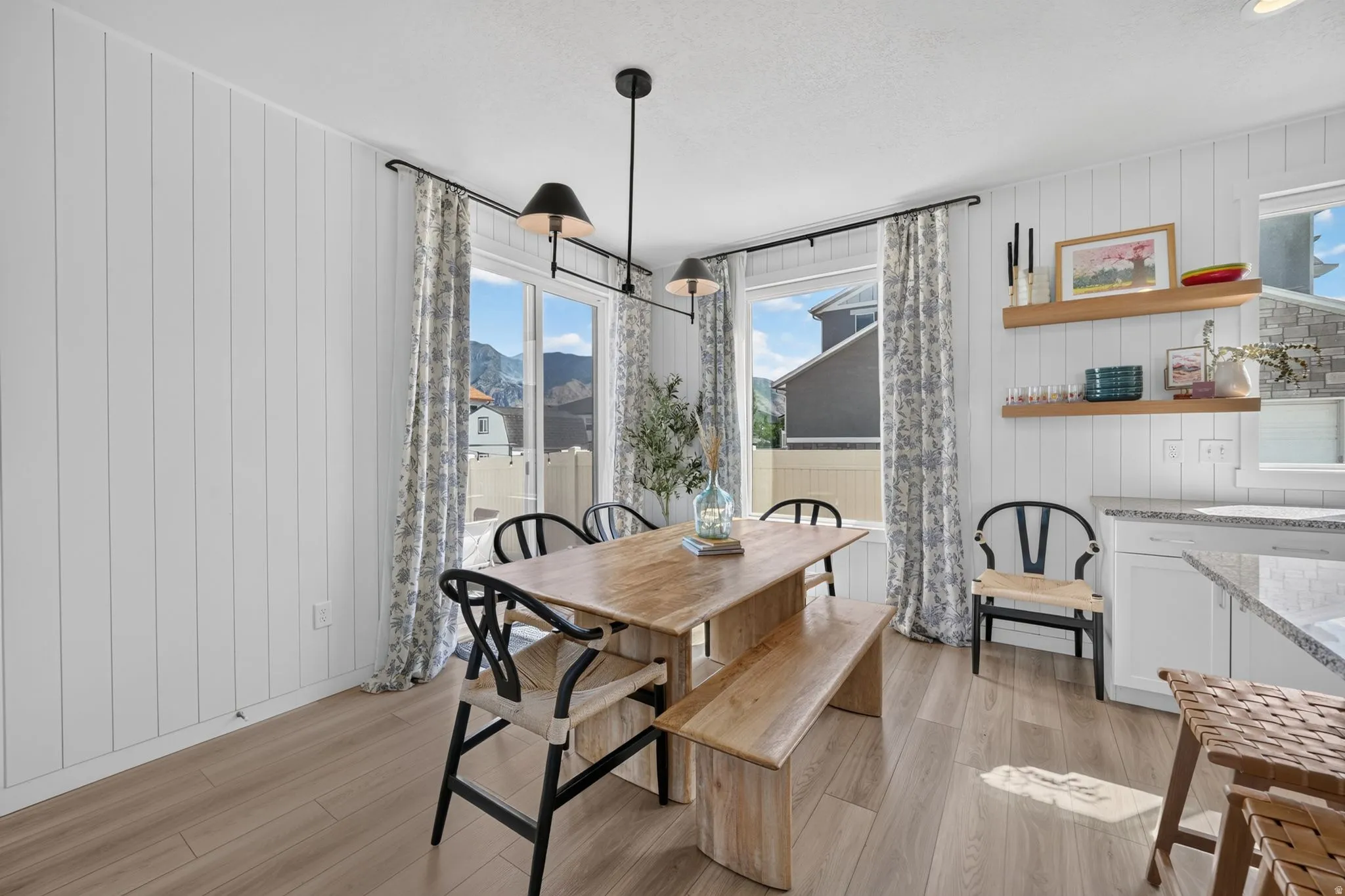 Panel accent walls, wood-finish flooring, linear pendant lighting, built-in open shelving, and sliding glass doors