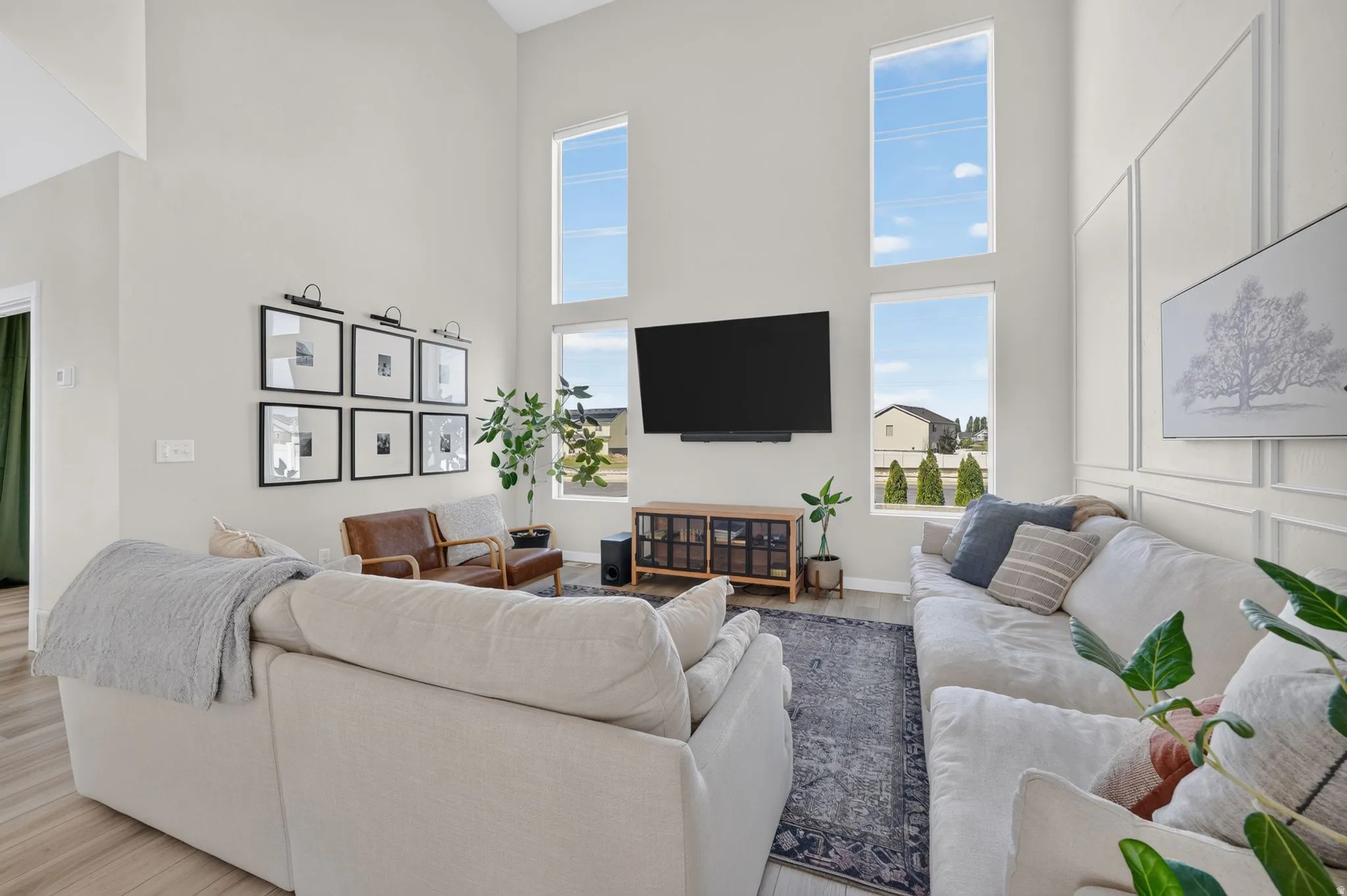 Double-height ceilings with stacked windows, plank flooring, and a decorative wall paneling accent