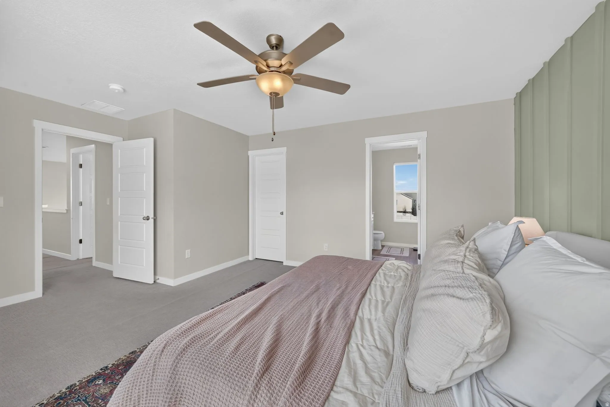 Carpeted room featuring a ceiling fan, a paneled accent wall, and multiple interior doors