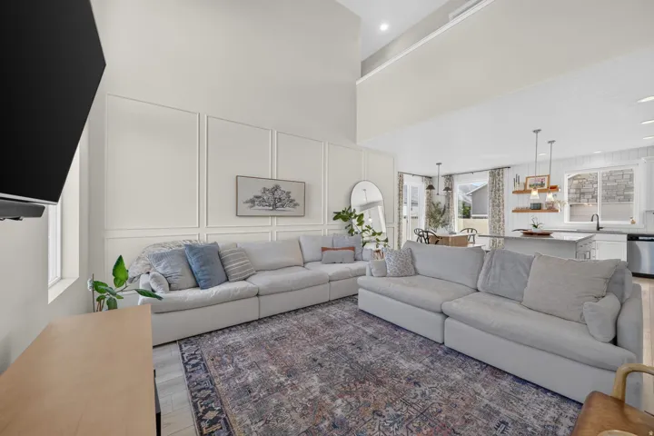 Open-concept living area with soaring ceilings, decorative wall paneling, and wood-finish flooring