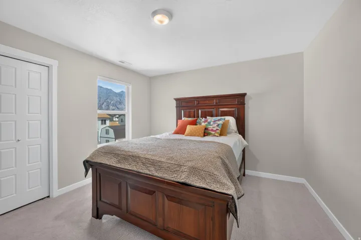 Neutral tone walls, ceiling-mounted light fixture, light grey carpeting, white trim, and a window with a mountain backdrop