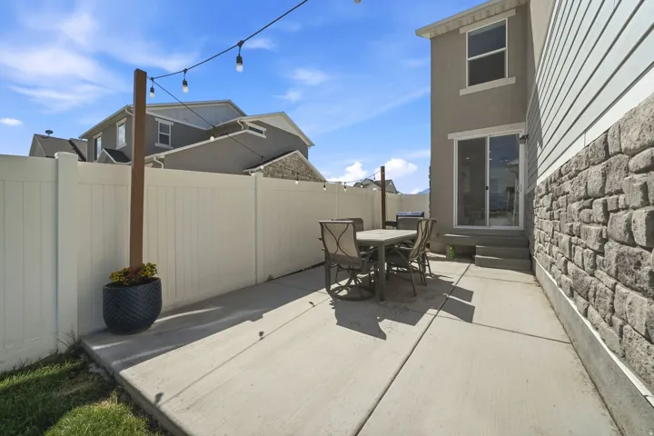 Concrete patio with a privacy fence, string lighting, and sliding glass door access