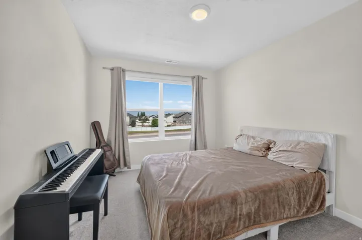 Carpeted flooring, vaulted ceiling, and a large window with neutral drapery