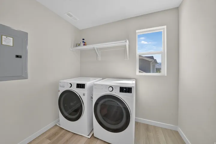 Laundry area featuring light wood-finish flooring, a white window, and a built-in white shelf