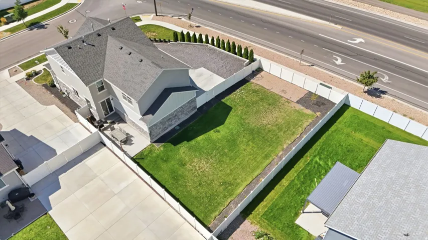 Expansive backyard with a manicured lawn, established privacy fencing, and a concrete patio