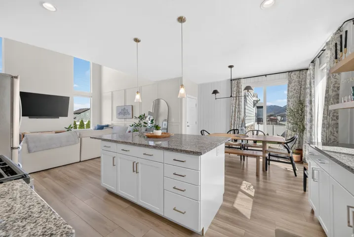Open-concept living area with wood-finish flooring, white cabinetry, and granite countertops