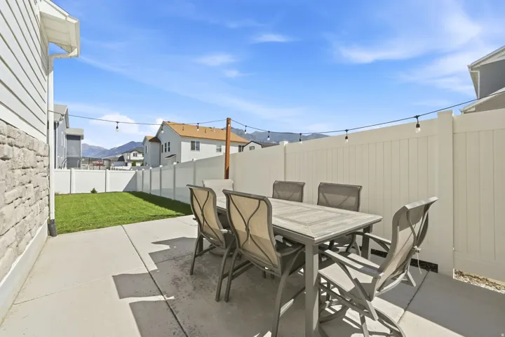 Private backyard featuring a concrete patio, perimeter fencing, and a manicured lawn