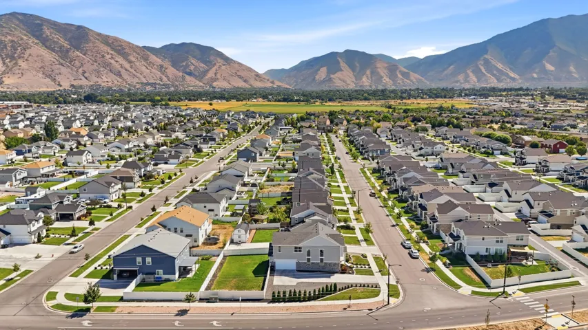 Expansive neighborhood setting with paved streets and sidewalks, surrounded by mountain scenery and open green spaces