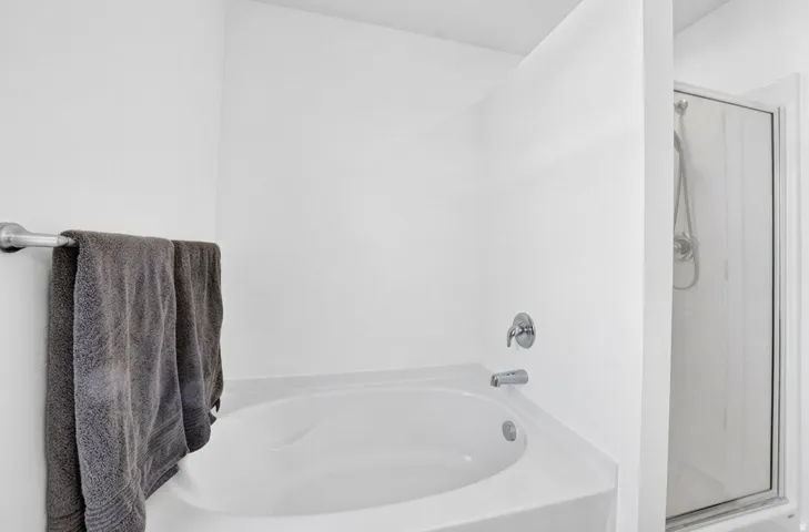 Built-in soaking tub with polished chrome fixtures and an adjacent glass-enclosed shower
