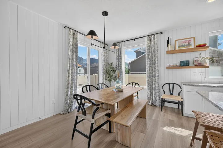 Panel accent walls, wood-finish flooring, linear pendant lighting, built-in open shelving, and sliding glass doors