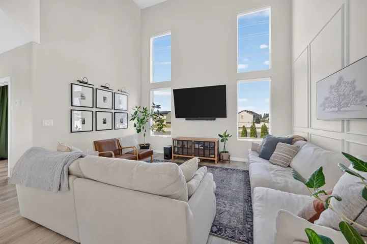 Double-height ceilings with stacked windows, plank flooring, and a decorative wall paneling accent