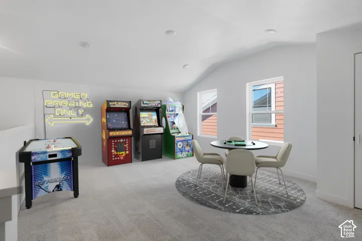 Loft space with vaulted ceiling, two windows, and light gray carpeting