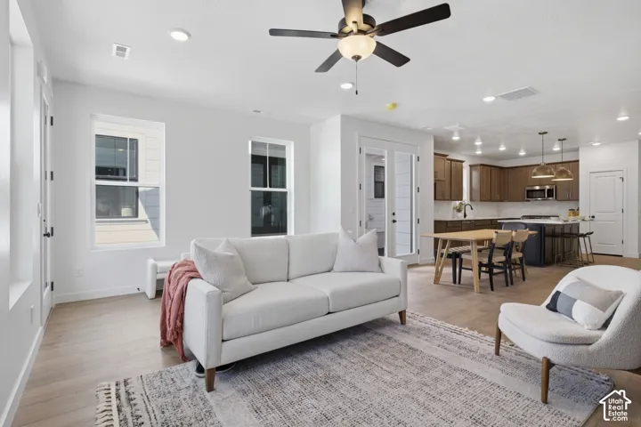 Wood tone floorng throughout, complemented by recessed lighting and a ceiling fan