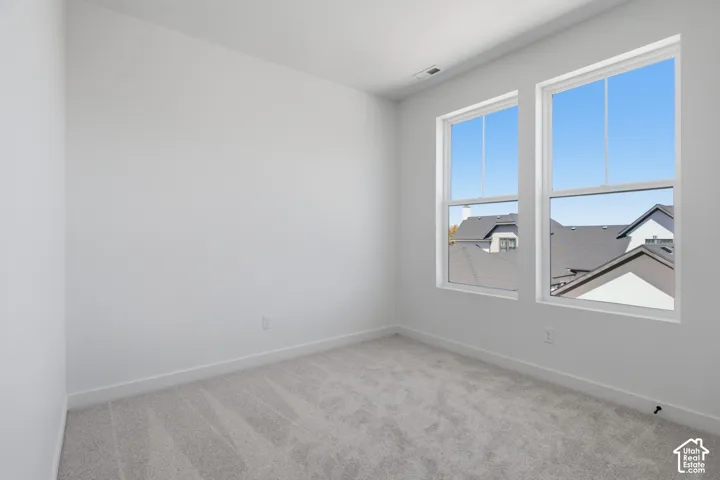 Guest bedroom with light gray carpeting, white walls, and two large windows
