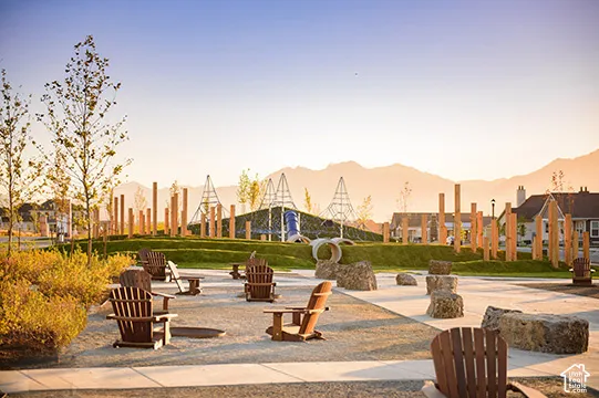 Expansive community green space featuring a play area, decorative wooden posts, and a gravel-paved gathering area with integrated boulders