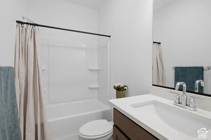 White tub-shower combination, dark wood-finish vanity with white countertop, integrated sink, and chrome fixtures
