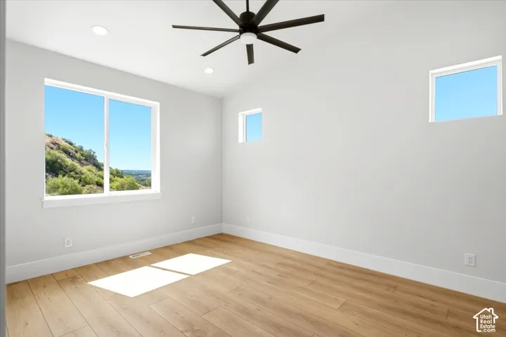 Vaulted ceiling with a contemporary ceiling fan, recessed lighting, wood-finish flooring, and multiple windows