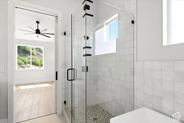 Glass-enclosed shower with pebble-tile floor and white square wall tiling