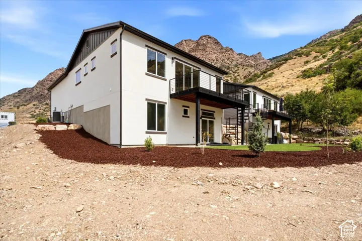 Contemporary multi-level exterior with white siding, multiple balconies with metal railings, and a spiral staircase