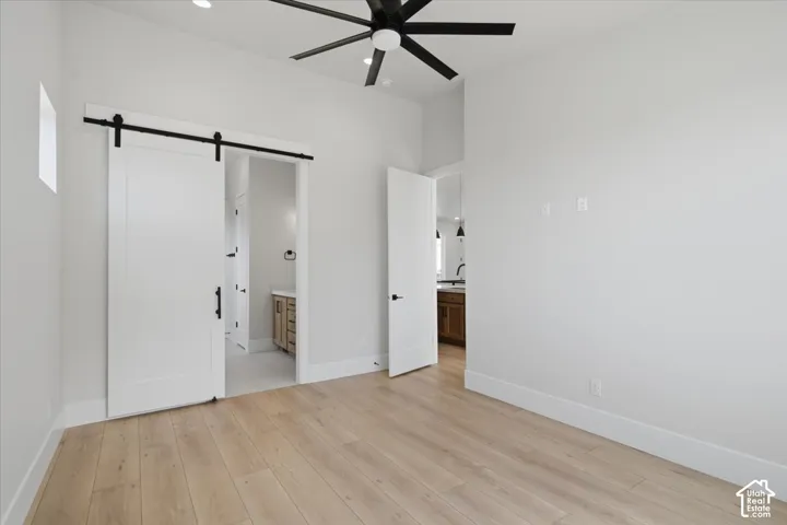 Light wood-finish flooring, white walls, and a black ceiling fan