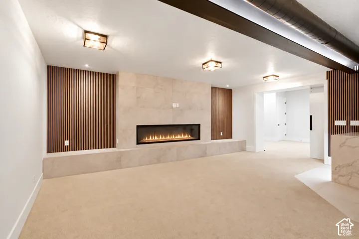 Linear fireplace featuring a stone-tile surround, vertical wood-slat accent wall, recessed lighting, and industrial-style exposed ductwork