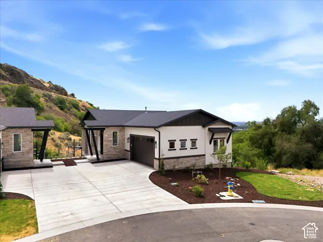 Contemporary exterior with stone veneer accents, an attached garage, a separate covered entry, and a concrete driveway
