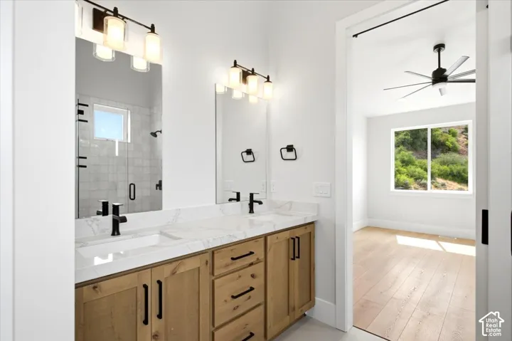 Dual vanity with quartz countertop, wood-finish cabinetry, and matte black fixtures