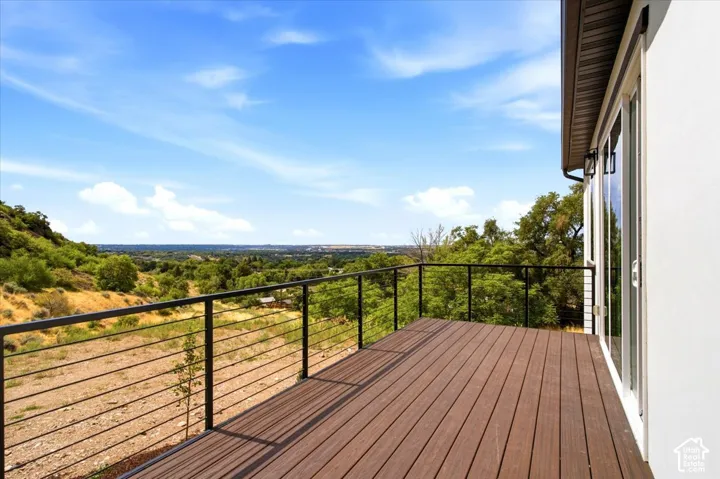 Outdoor deck with wood-finish flooring, black metal cable railing, and white exterior wall