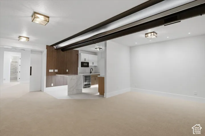 Open concept recreation space featuring a wet bar with white cabinetry, a built-in microwave, and a beverage refrigerator