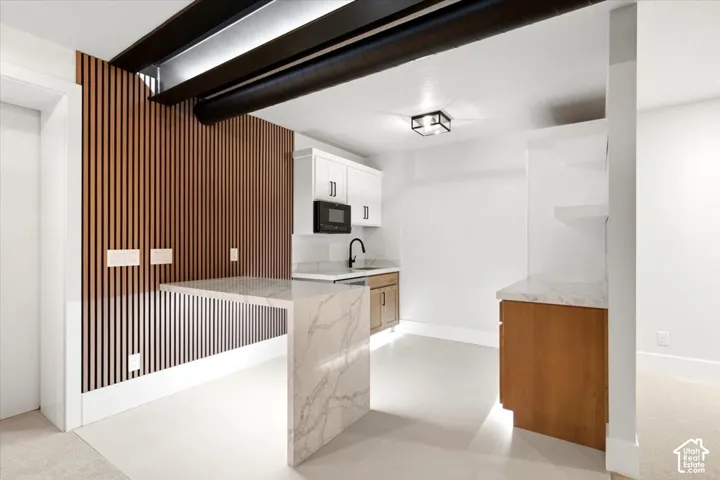 Modern kitchenette featuring white cabinetry, a built-in microwave, and a black faucet