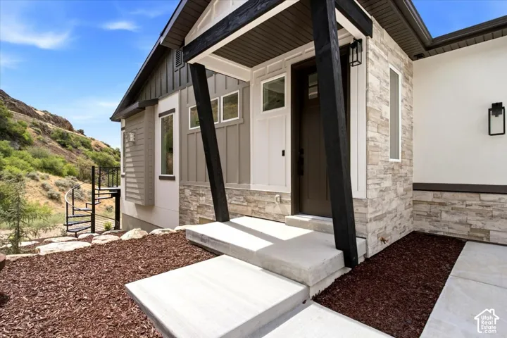 Contemporary exterior featuring stone veneer accents, vertical siding, a dark wood-finish entry door, and a spiral staircase
