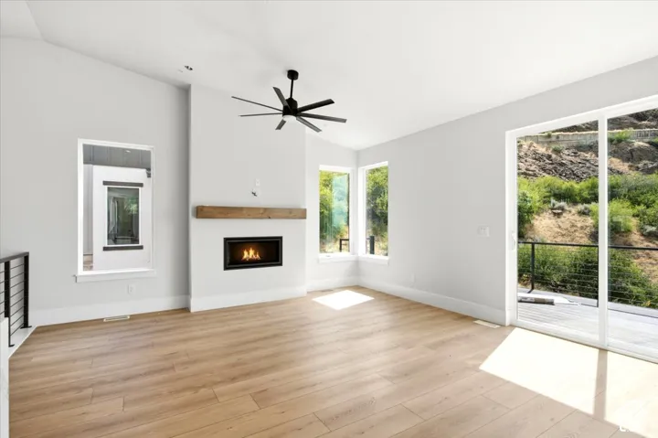 Light wood-finish flooring, vaulted ceilings, and a modern fireplace with a wood mantle