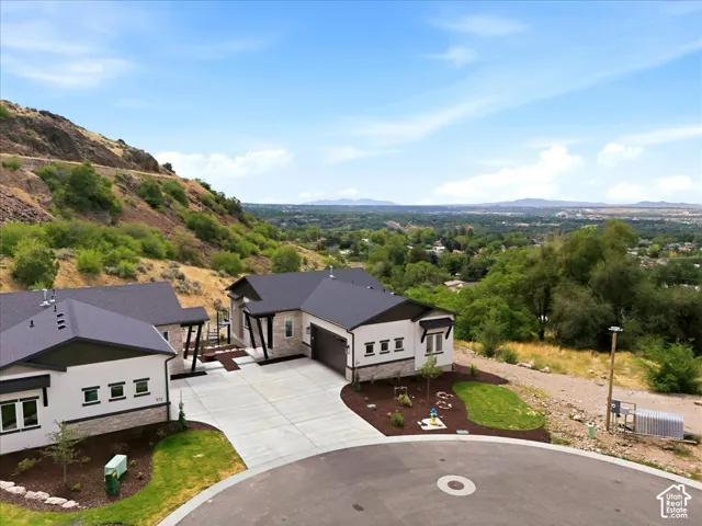Modern architecture with stone accents, an attached garage, a concrete driveway, and a landscaped yard