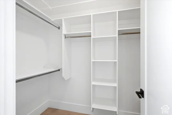 White built-in shelving, multiple hanging rods, and dark bronze door hardware