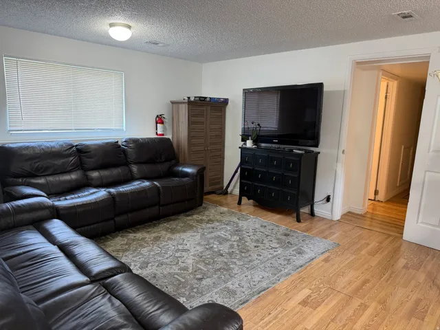 Wood-finish flooring, white walls, and a window with horizontal blinds