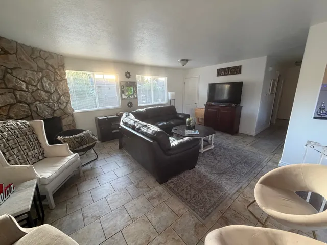 Stone-clad fireplace feature, tiled flooring, multiple windows, recessed lighting, and a white paneled door